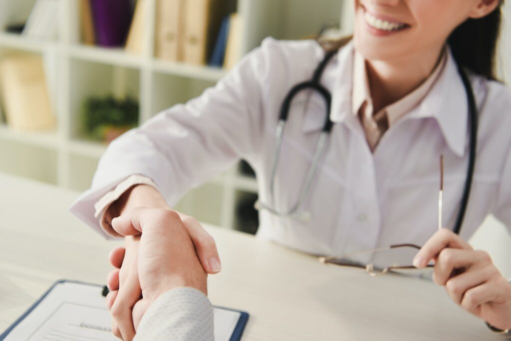cropped view of client and doctor shaking hands in office